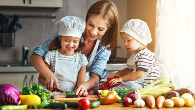 Happy family mother and children prepares vegetable