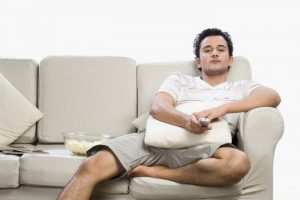 A man sitting on a sofa exposed to the dangers of prolonged sitting