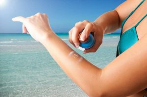 Woman applying spray sunscreen on her hand