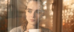 A woman behind the window wearing sunscreen indoors